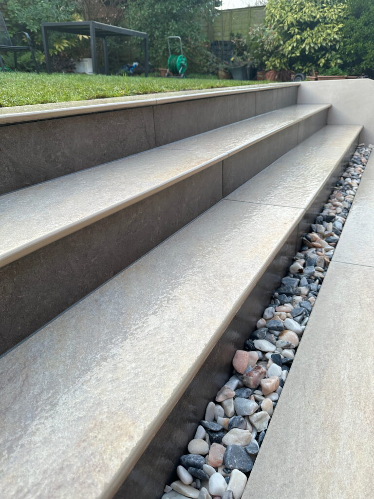 The image features elegant outdoor stairs with sleek stone steps and a decorative gravel bed alongside