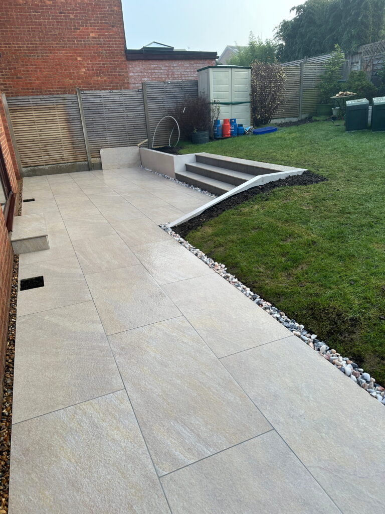 A well-designed backyard features a tiled patio, steps, and landscaped areas with gravel and greenery