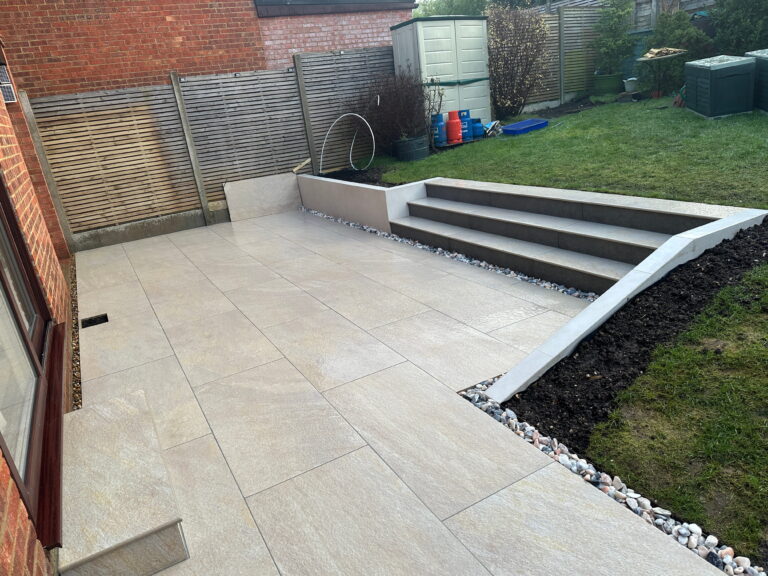 A modern patio featuring large stone tiles, elegant steps, and landscaped borders, ideal for outdoor relaxation