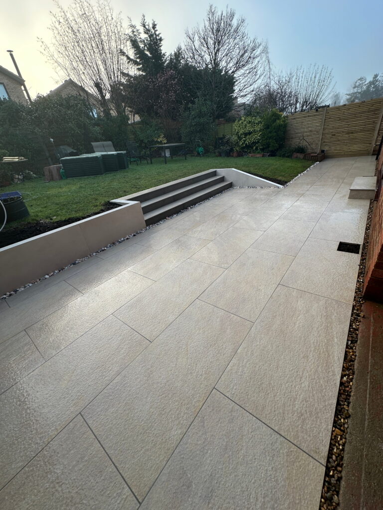 A modern garden featuring smooth paving, steps, and greenery, creating a tranquil outdoor space