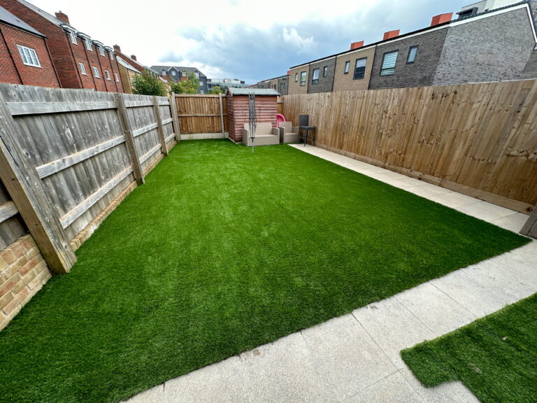 Modern garden with lush artificial grass, wooden fences, and patio, ideal for outdoor relaxation and entertainment