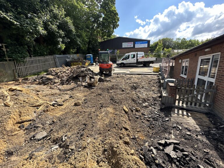 An outdoor construction site with machinery, debris, and a fenced area. Sunlight breaks through scattered clouds