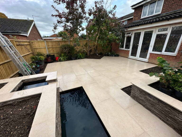 A modern backyard with patio tiles, water features, and lush plants, showcasing a cozy outdoor space
