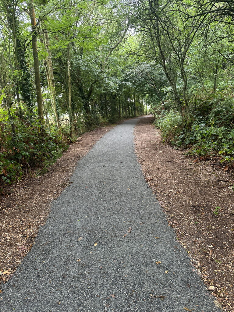A winding gravel path surrounded by lush greenery and trees, inviting exploration and peaceful walks in nature