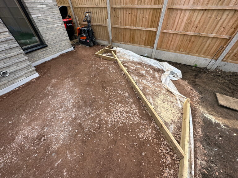 A construction area with fresh dirt, wooden framing, and equipment like a compactor and tools