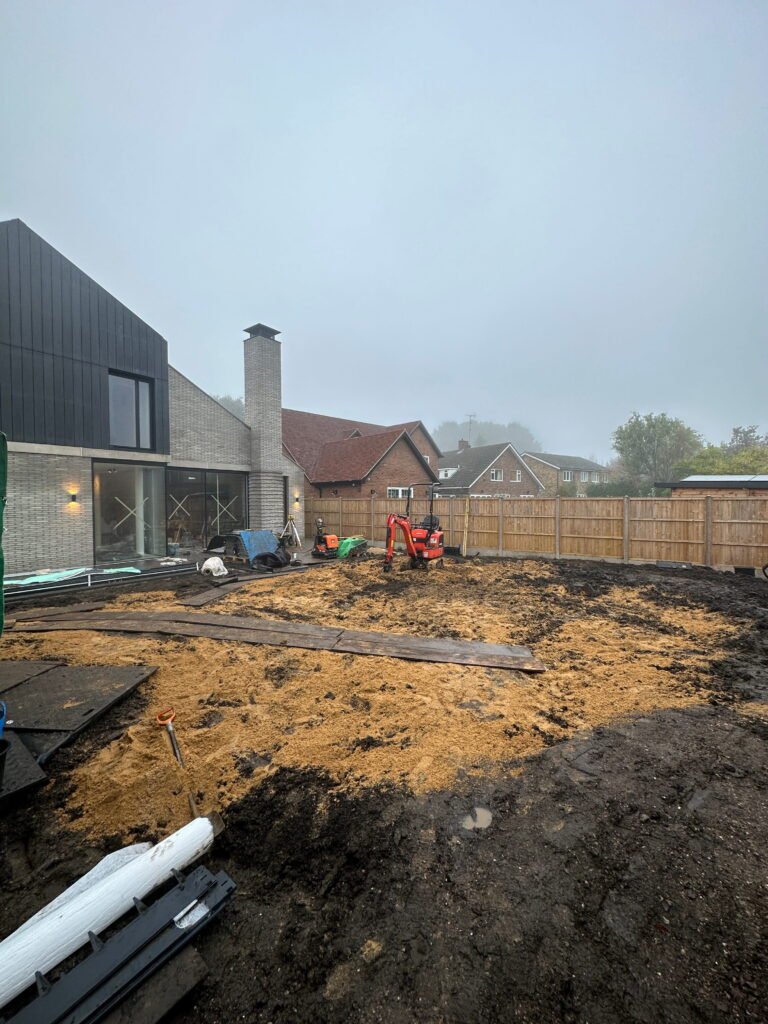 A construction site features a foggy backdrop, with machinery on disturbed soil and a modern building under progress
