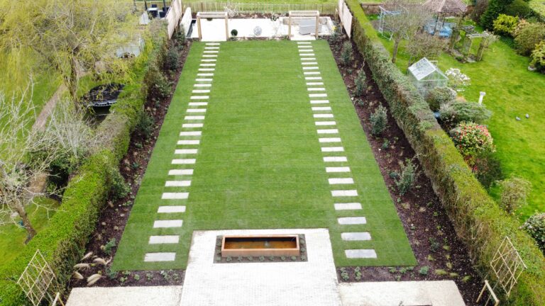 Lush green garden featuring a modern stepping stone pathway and tranquil water feature, surrounded by neatly trimmed hedges