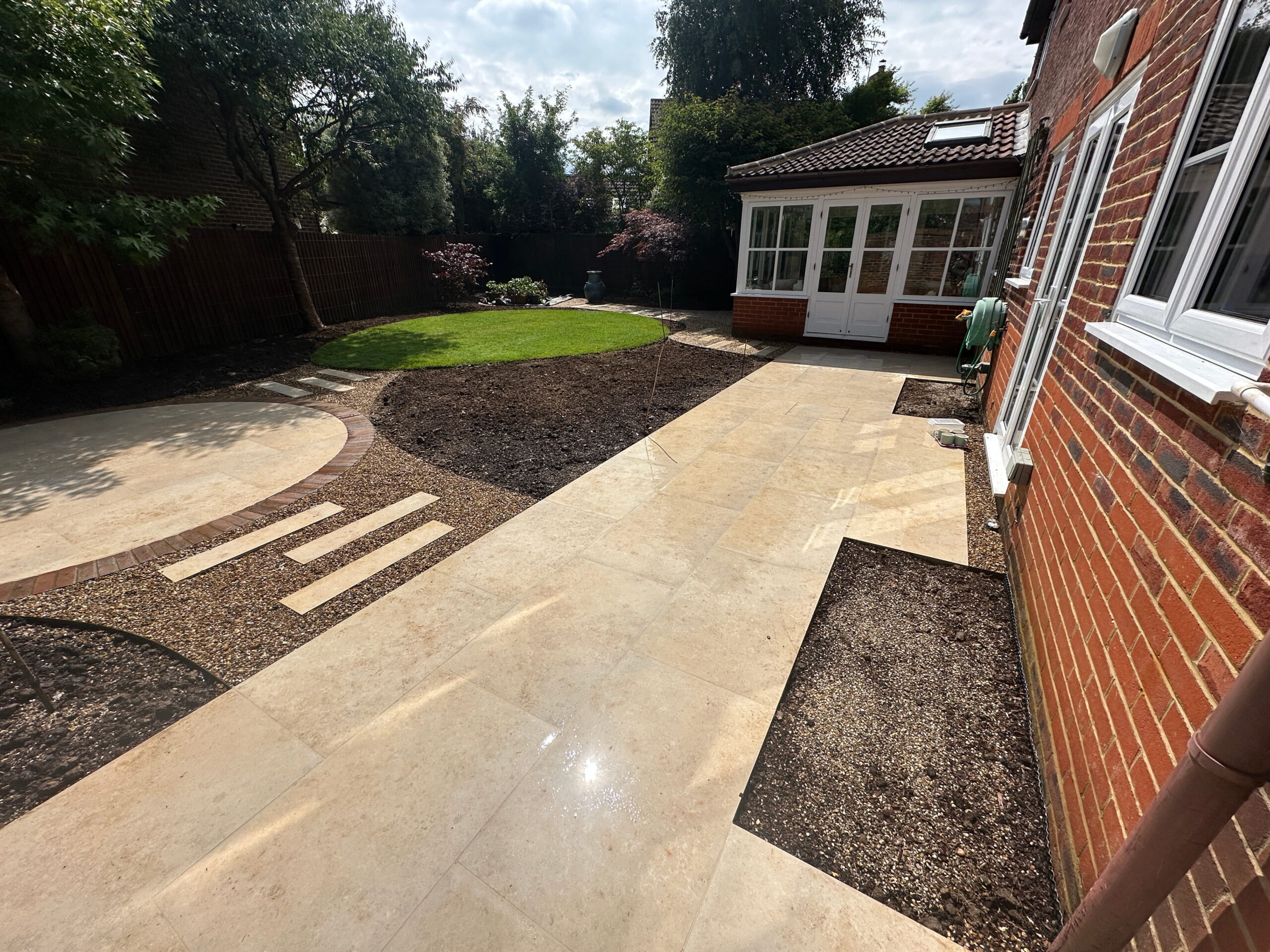 Modern garden patio design featuring elegant stone pathways, manicured lawn, and a stylish conservatory for outdoor living