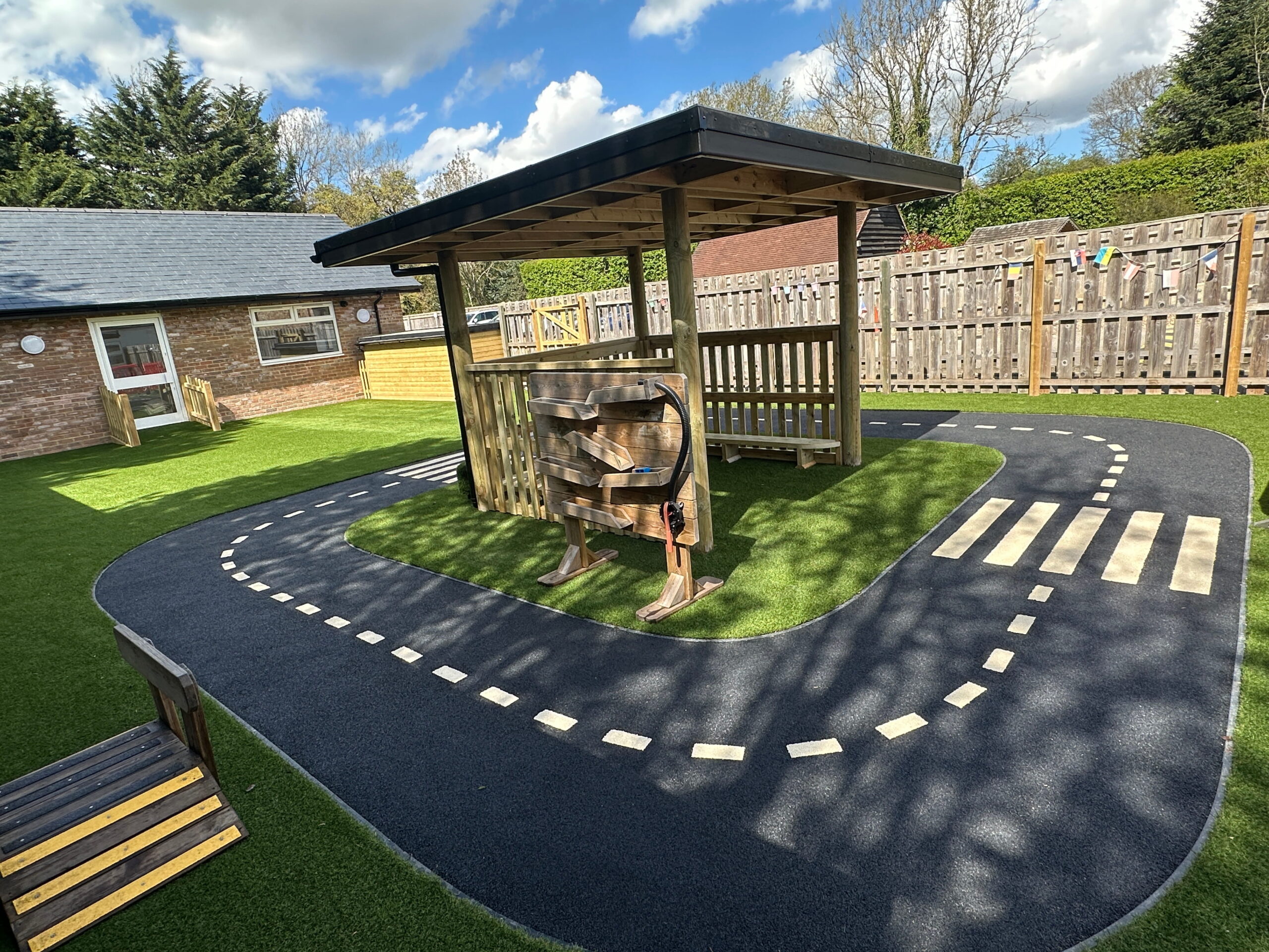 Playground with a winding path, gazebo, and vibrant greenery, ideal for children's outdoor activities and learning