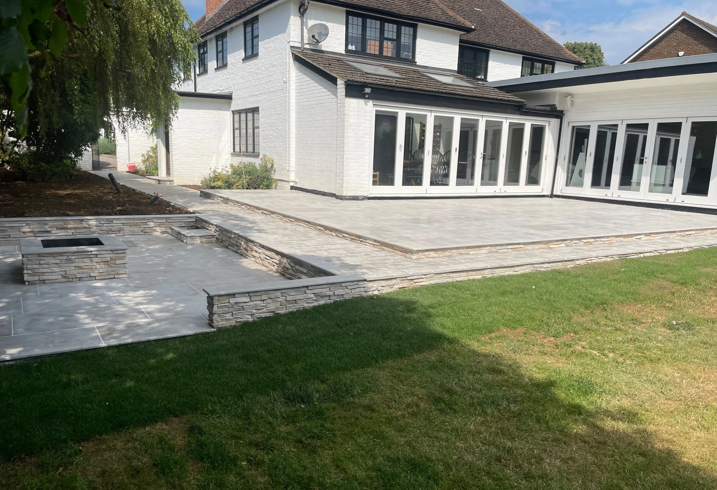 A modern home with a spacious patio, stone features, and a green lawn creates a stylish outdoor living space